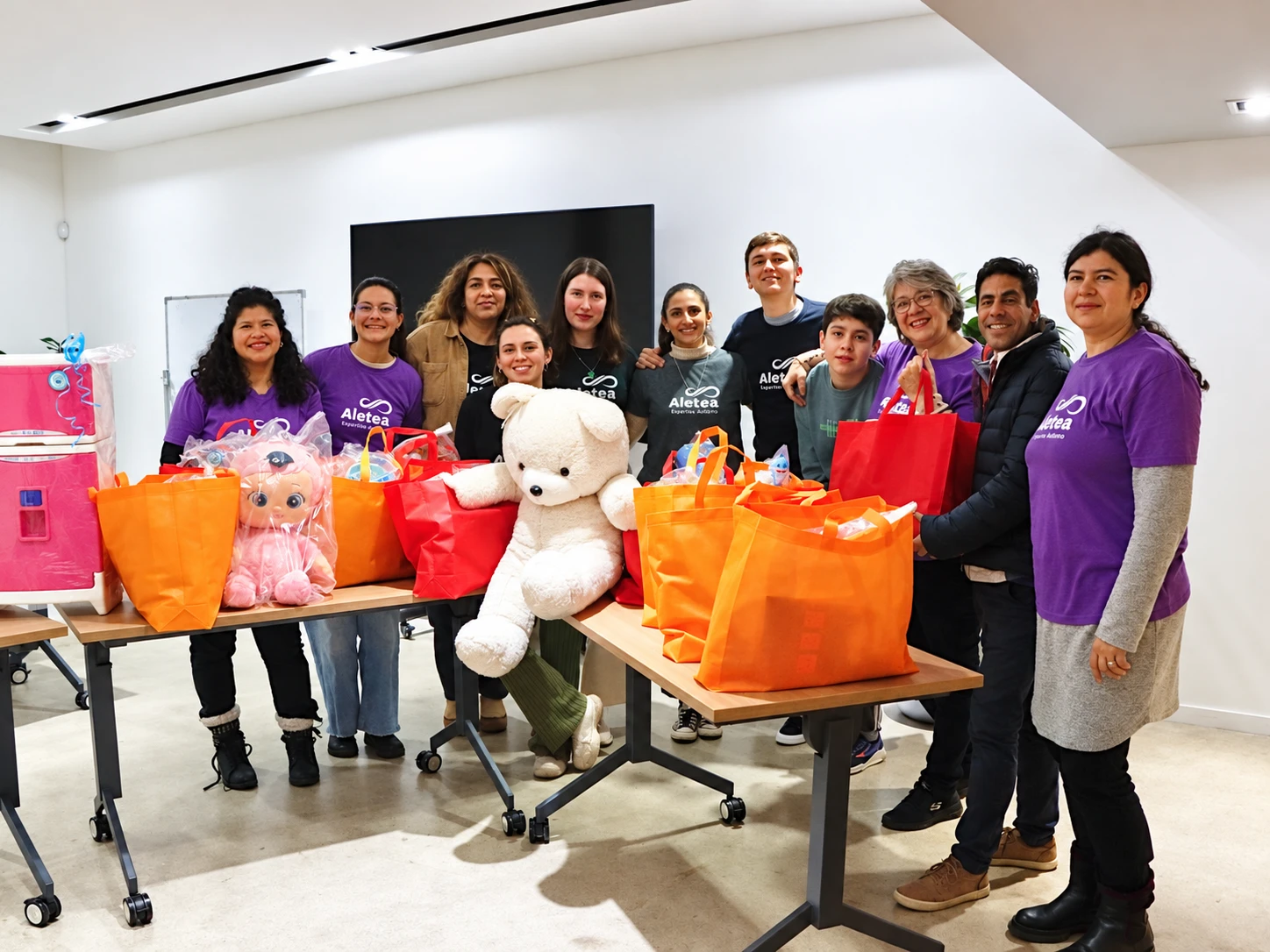 Grupo de personas detrás de mesas con bolsas, cajas y juguetes.