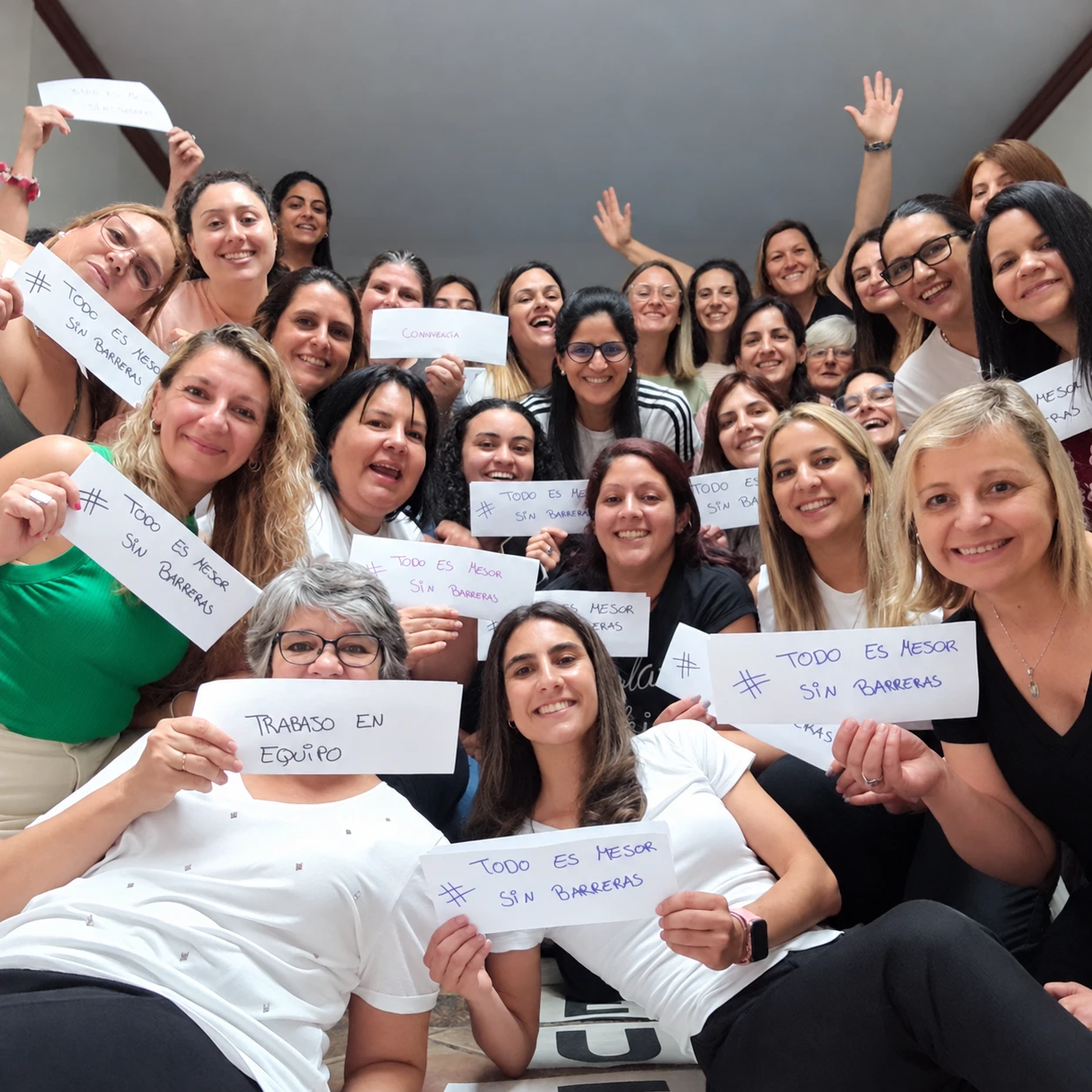 Grupo de personas reunidas con carteles manuscritos sobre convivencia y trabajo en equipo.